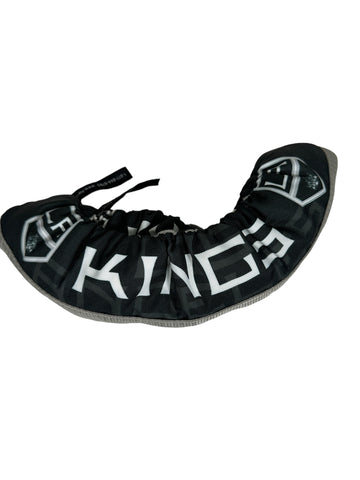 Black Skate soakers with a reinforced silver bottom. On the sides are black, featuring the word "KINGS" along with the 2 LA Kings Shield logos, preceding and following the word, respectively. Tucked within the outer skate guard is the second skate guard. Both skate guards feature black pull tabs, for easier use. 

The skate guards are on a blank, white background. 